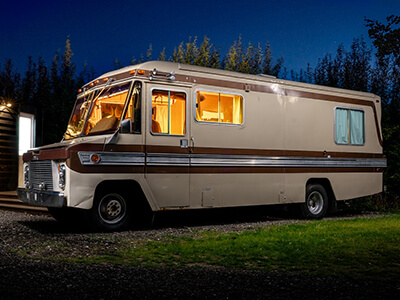 Alabama an American RV, shown at night with a cosy warm glow from the windows.