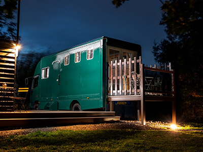 Gee Gee a green Horse lorry with a raised deck, shown at night nestled among the trees.