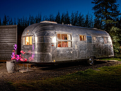 Peggy Sue, a1950's Airstream pictured at night with pink flamingo neon lights.